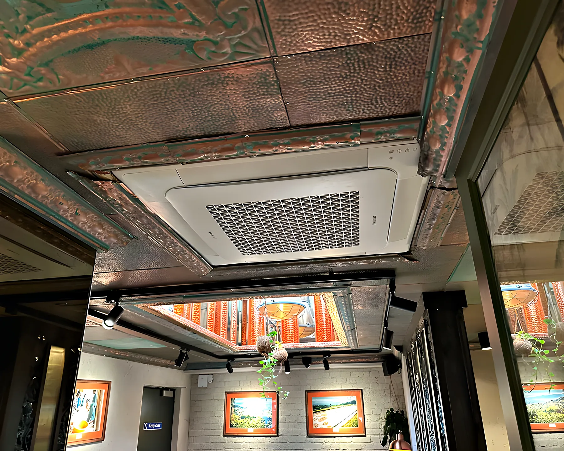 A ceiling cassette set into a pressed tin ceiling above a bar