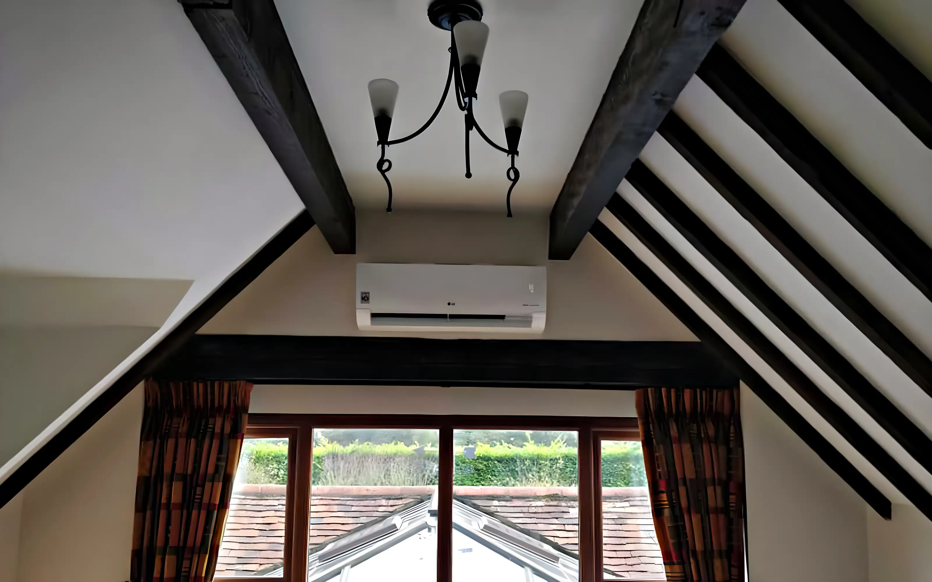 A wall mounted air conditioning unit fitted between the oak beams of a garden room