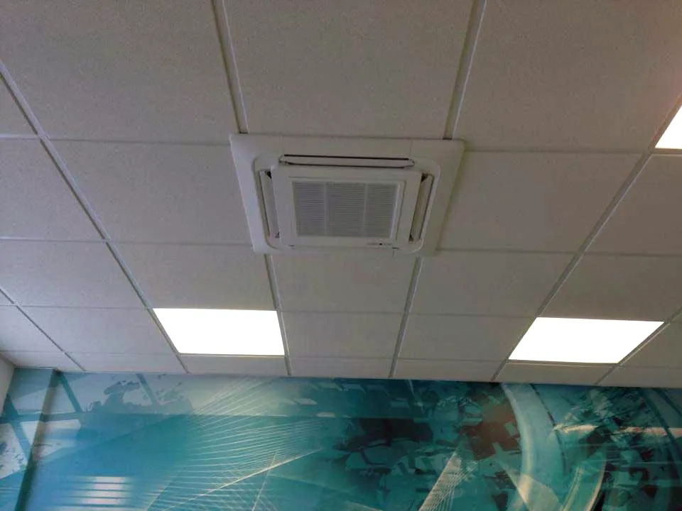 A ceiling cassette set flush into a suspended ceiling between the light panels