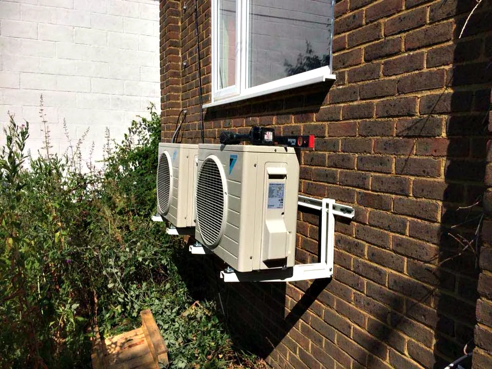 Outdoor units on wall brackets beside a cottage