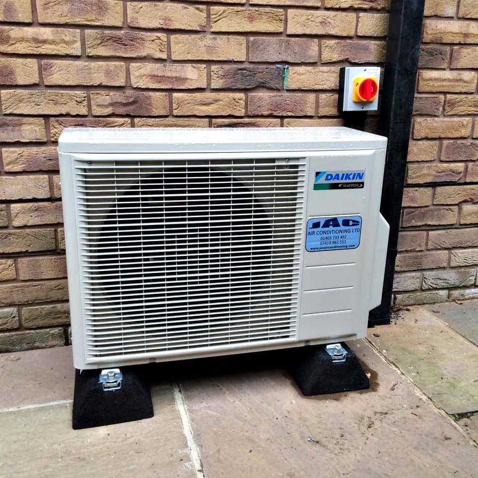 A Daikin outdoor unit on anti vibration feet against a brick wall