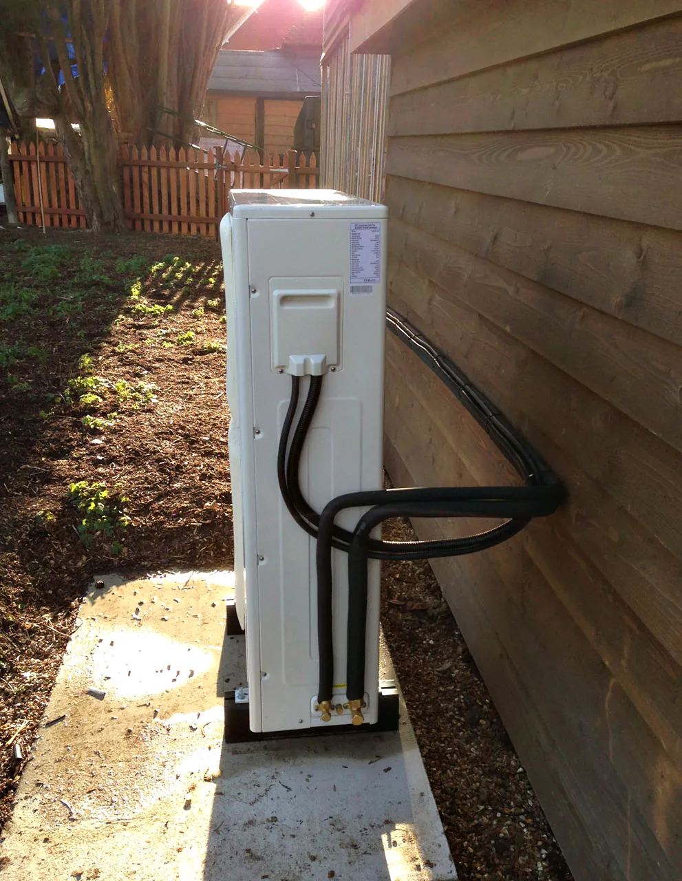 An outdoor unit on brackets beside a timber garden room