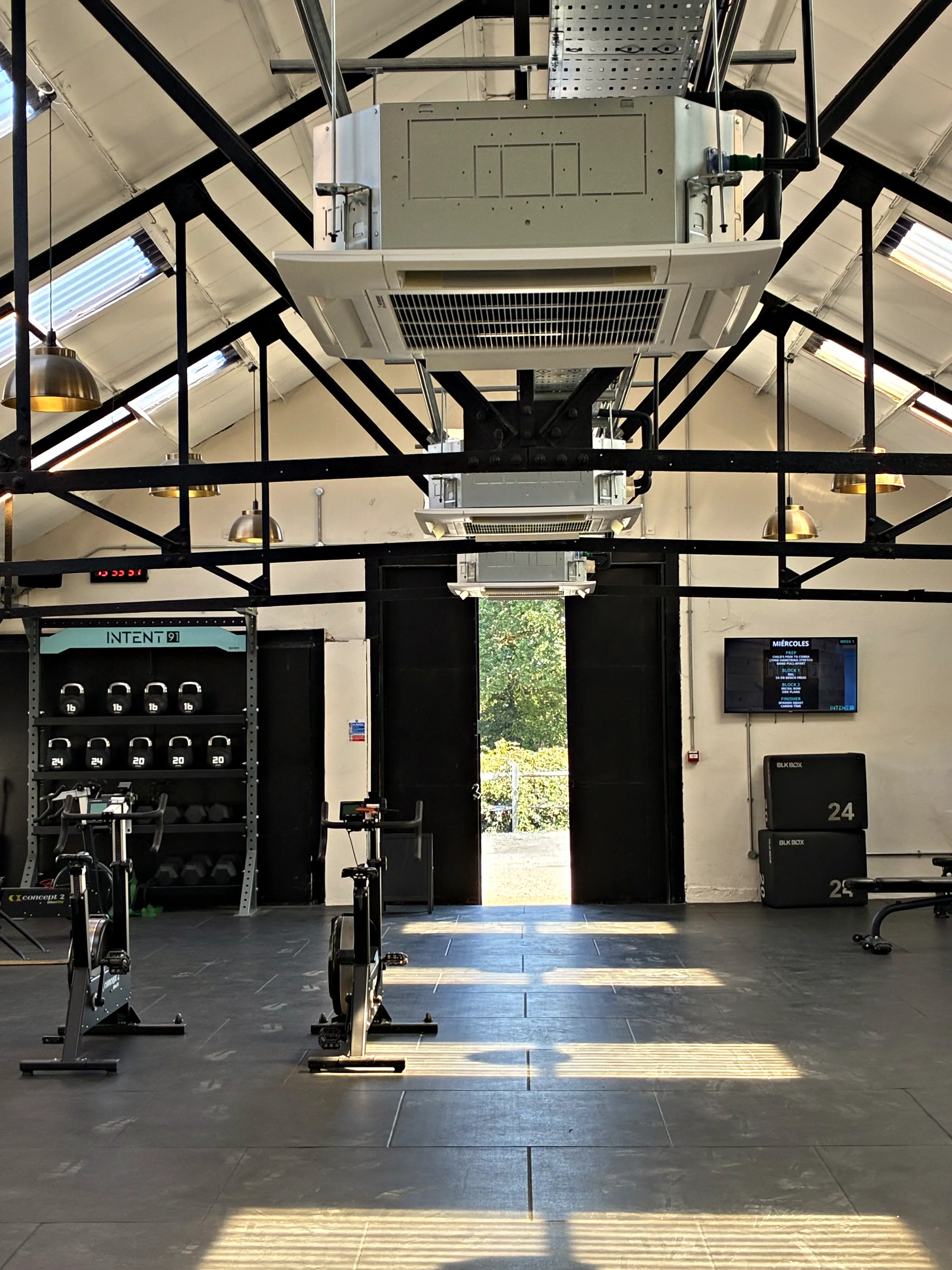 Ceiling cassettes hung from the steel roof trusses of a commercial gym