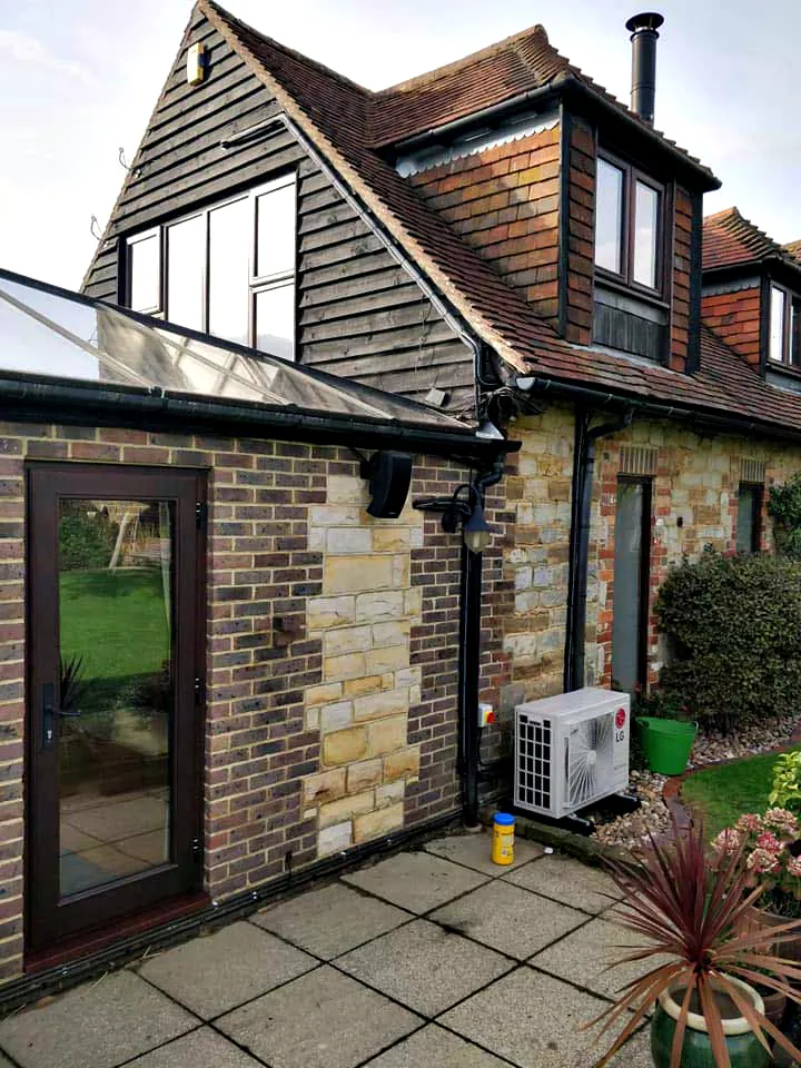 An outdoor unit beside a tile hung house