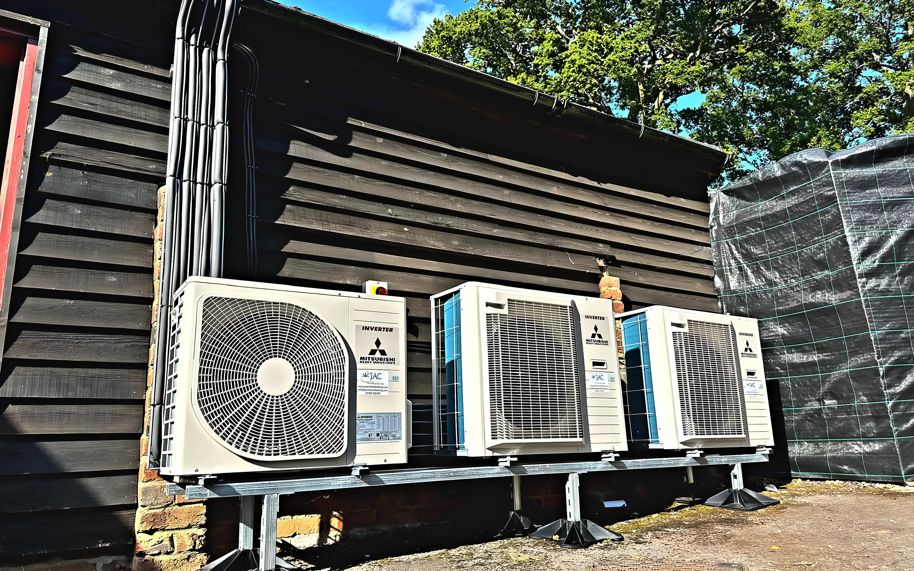 A bank of Mitsubishi Heavy Industries outdoor units against a black weatherboarded wall