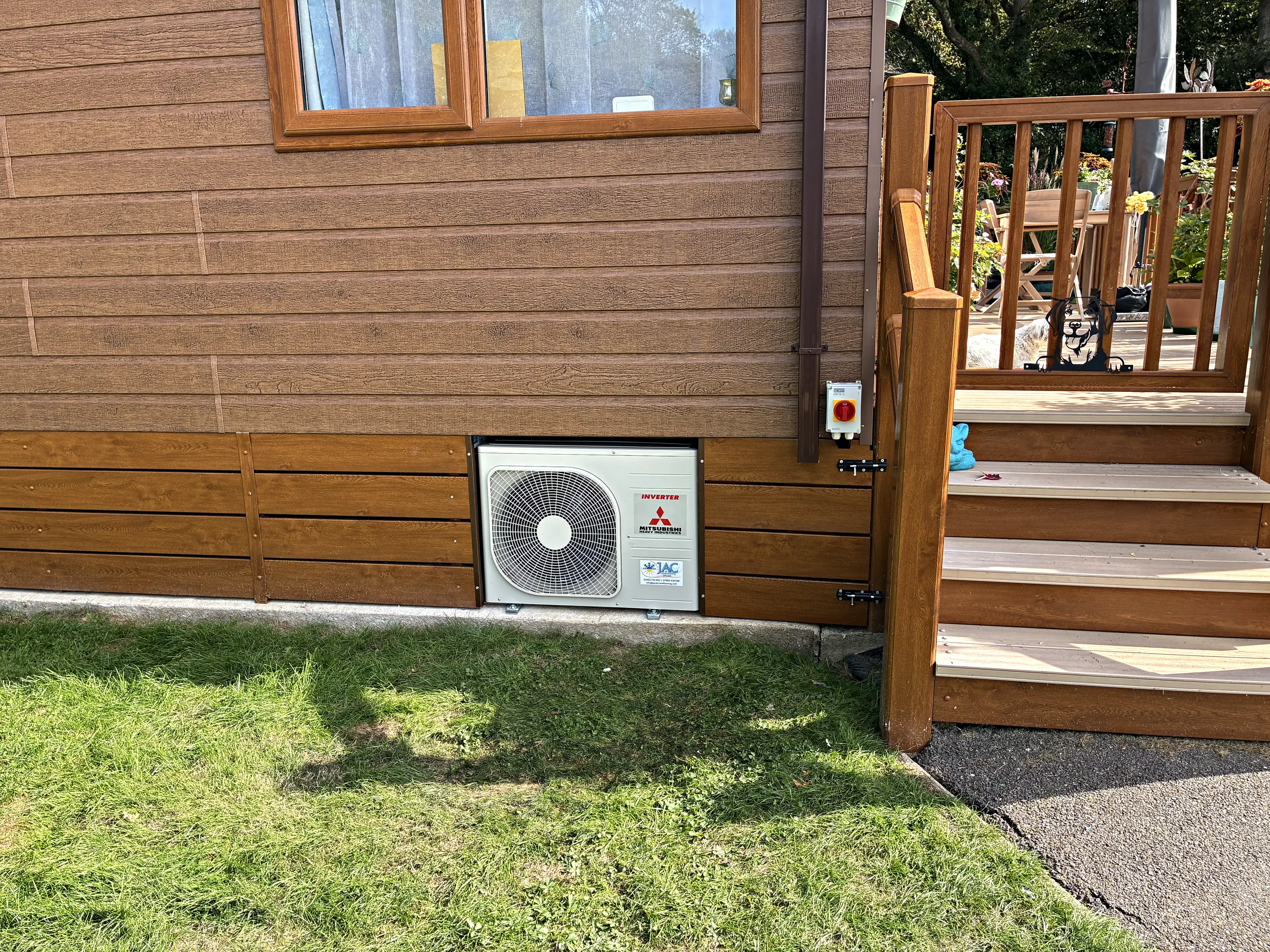 An outdoor unit fitted neatly into the skirting of a park home beside the steps up to the decking