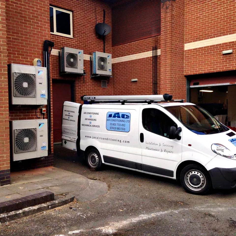 A JAC Air Conditioning van parked beside outdoor units on a commercial job